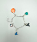 Sterling silver charm bracelet with sea glass from Spain and Japan, seashell, fossilized shark tooth, and mermaid maker’s mark tag.