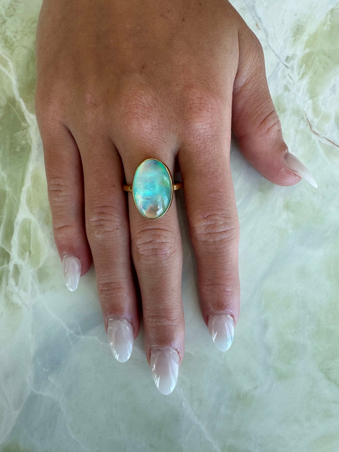Gold vermeil ring featuring iridescent Aurora opal with shifting hues of blue, pink, and green, set in sterling silver base with thick gold plating