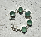 Bracelet with green circular sea glass on a textured surface