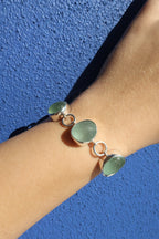 Green bracelet on a wrist against a blue background