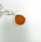 Historic charm bracelet featuring Sicilian red-glow black sea glass, fossilized shark tooth, and amber sea glass from England, set in sterling silver.