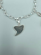 Historic charm bracelet featuring Sicilian red-glow black sea glass, fossilized shark tooth, and amber sea glass from England, set in sterling silver.