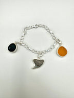 Historic charm bracelet featuring Sicilian red-glow black sea glass, fossilized shark tooth, and amber sea glass from England, set in sterling silver.