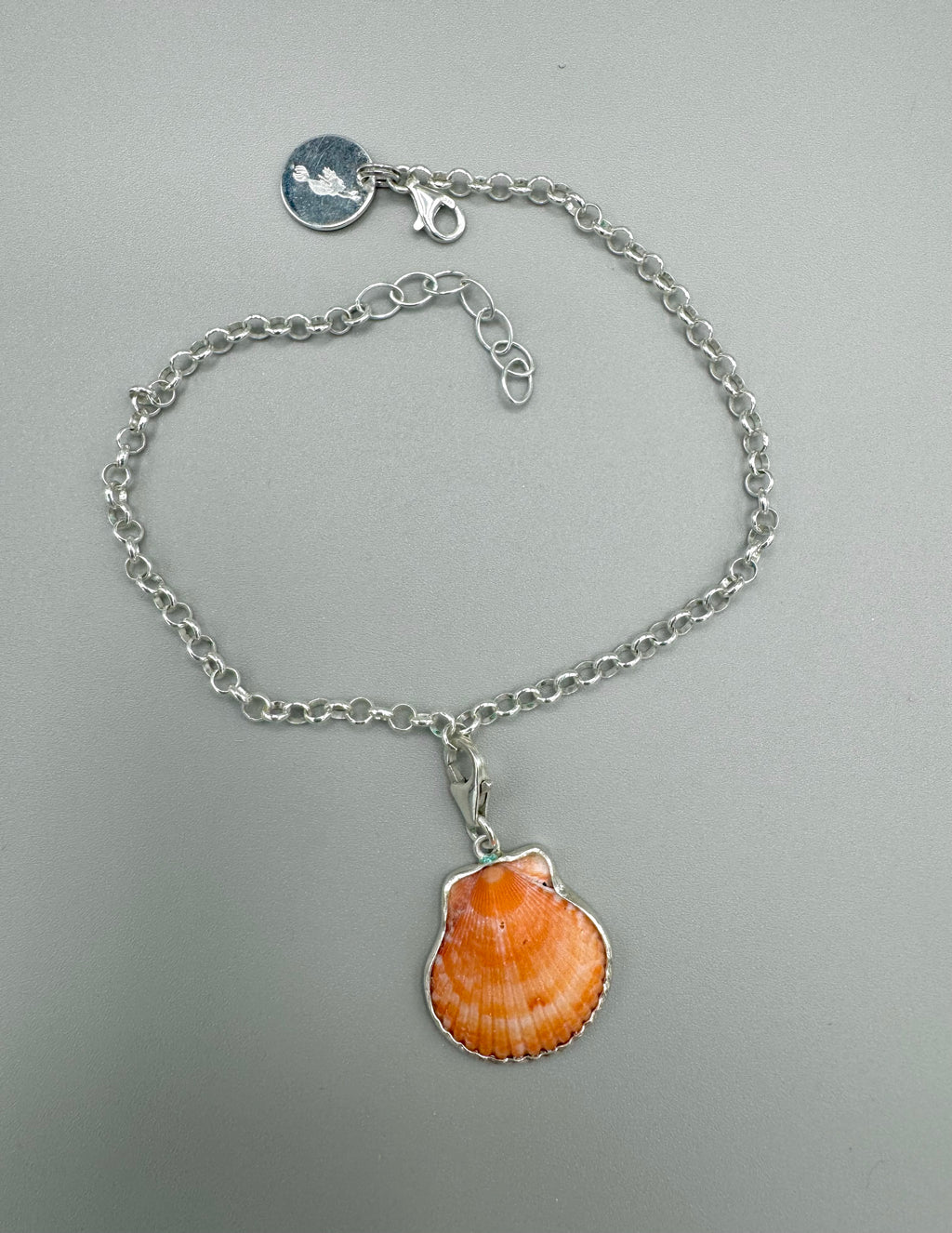 Sterling silver adjustable ankle bracelet featuring a pink scallop shell charm and swimming mermaid logo tag from southwest Florida.