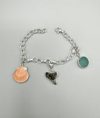 Sterling silver charm bracelet with pink scallop shell, fossilized shark tooth, and aquamarine sea glass from Japan — ocean-inspired handcrafted jewelry.