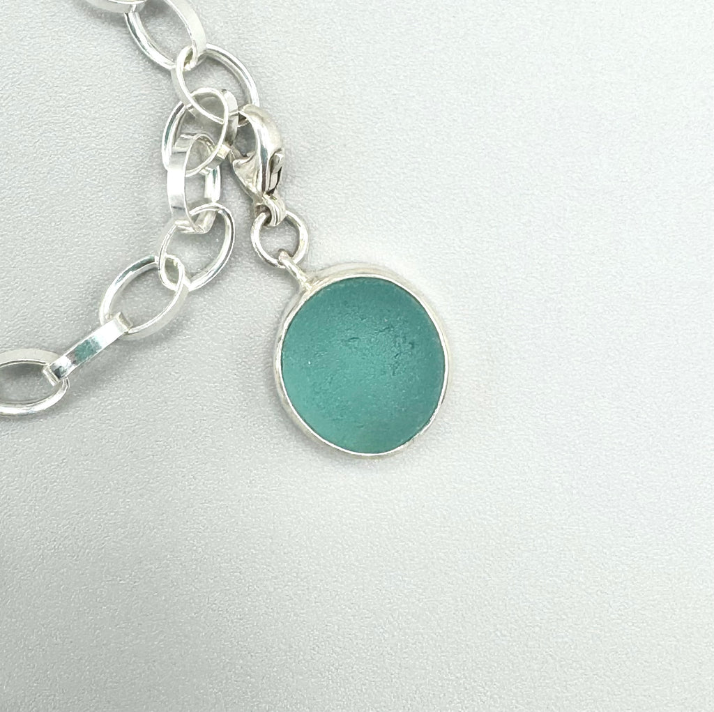 Sterling silver charm bracelet with pink scallop shell, fossilized shark tooth, and aquamarine sea glass from Japan — ocean-inspired handcrafted jewelry.