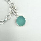 Sterling silver charm bracelet with pink scallop shell, fossilized shark tooth, and aquamarine sea glass from Japan — ocean-inspired handcrafted jewelry.