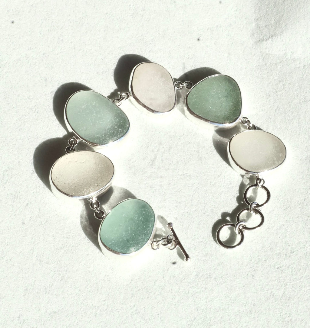 Sterling silver bracelet featuring alternating pieces of white and sea foam Sicilian sea glass with adjustable clasp.