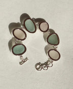 Sterling silver bracelet featuring alternating pieces of white and sea foam Sicilian sea glass with adjustable clasp.
