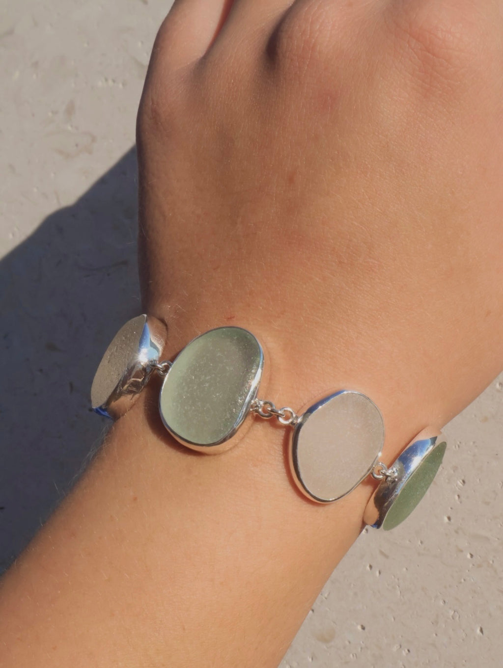 Sterling silver bracelet featuring alternating pieces of white and sea foam Sicilian sea glass with adjustable clasp.