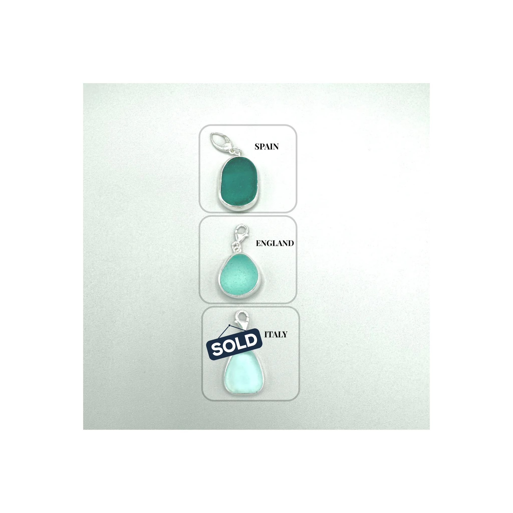 Three teal teardrop-shaped charms on cards labeled 'Spain', 'England', and 'Italy' against a white background.