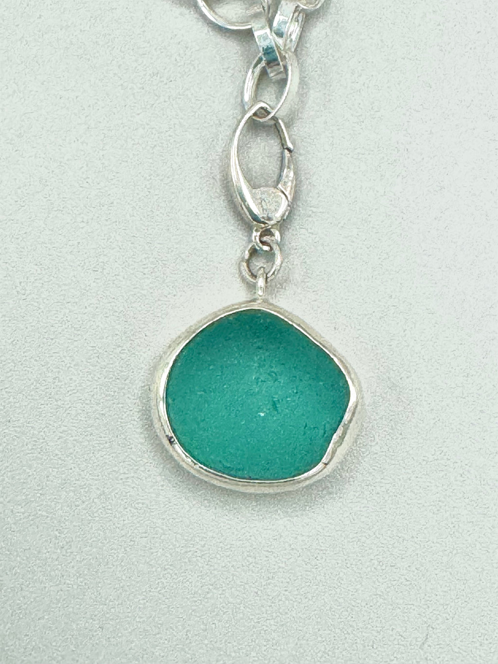 Sterling silver charm bracelet featuring seafoam green sea glass, fossilized shark tooth, and turkey wing shell.