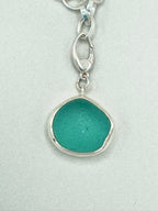 Sterling silver charm bracelet featuring seafoam green sea glass, fossilized shark tooth, and turkey wing shell.