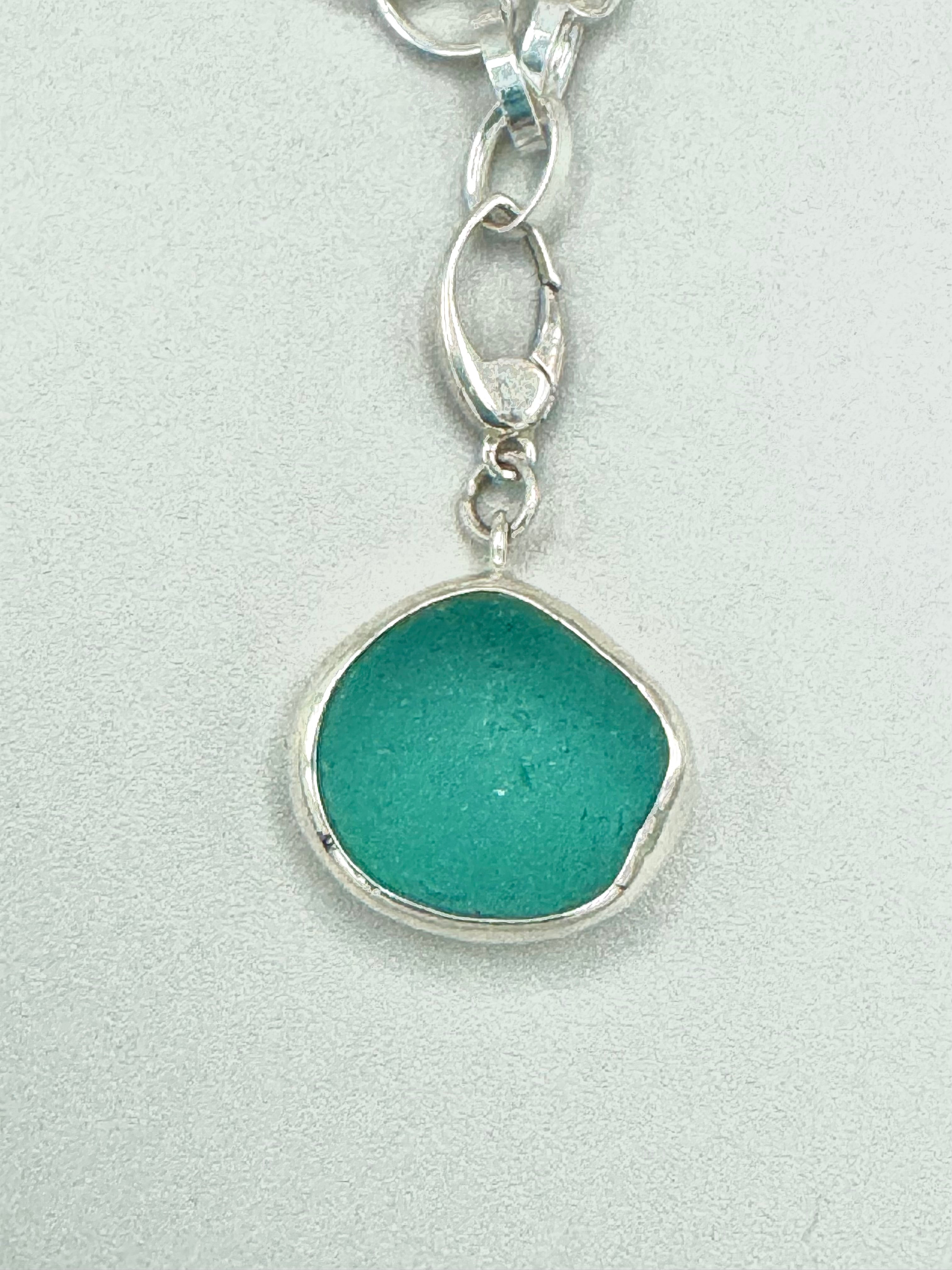 Sterling silver charm bracelet featuring seafoam green sea glass, fossilized shark tooth, and turkey wing shell.