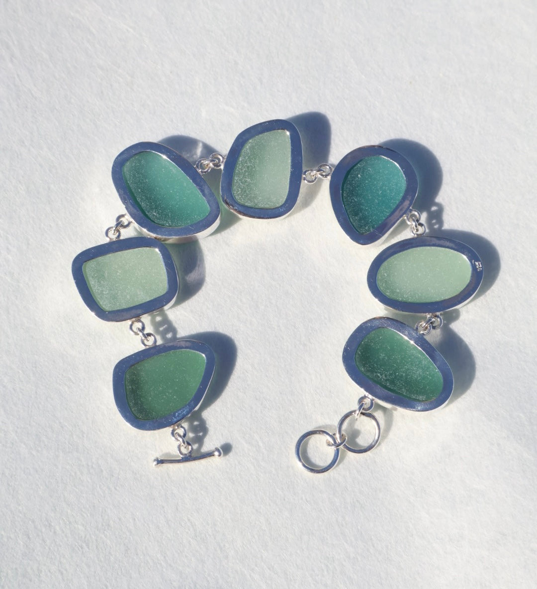 Sterling silver bracelet featuring alternating teal and sea foam Italian sea glass pieces with an adjustable clasp