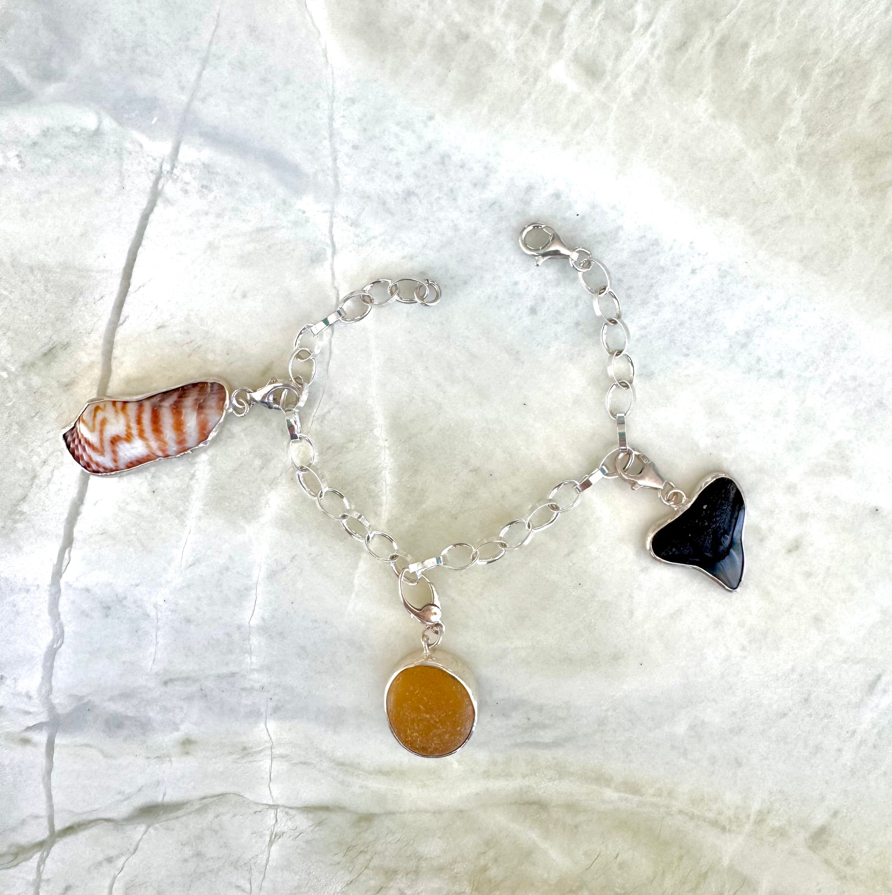 Sterling silver rolo link charm bracelet with yellow-gold sea glass from England, fossilized shark tooth, and turkey wing shell from Casey Key, Florida.